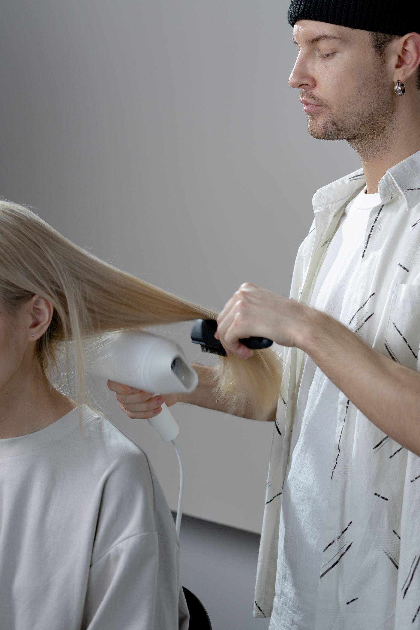 Stylist blow-drying a client's long blonde hair