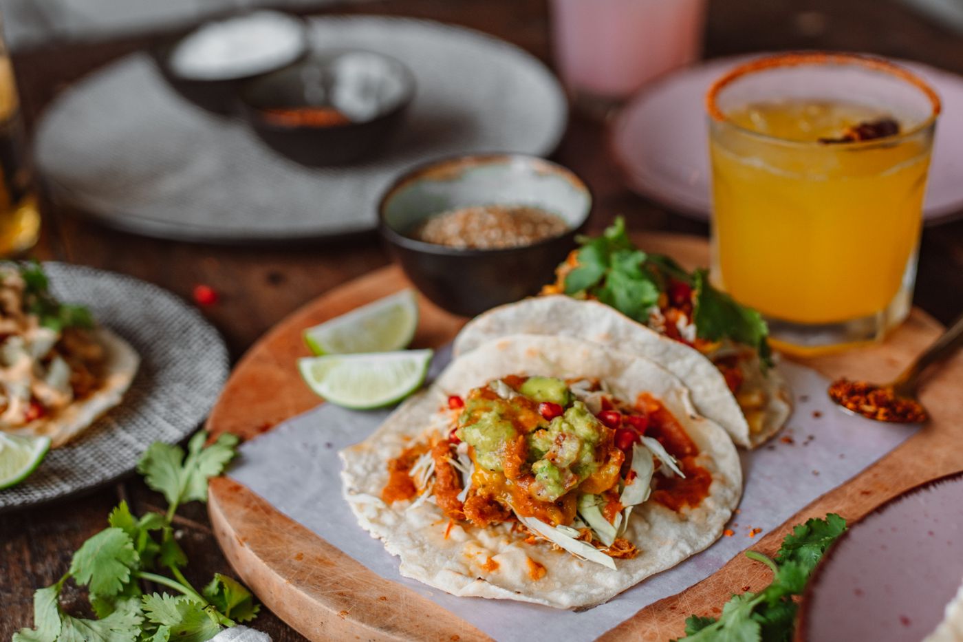 Tacos with guacamole and a mezcal cocktail on a wooden board