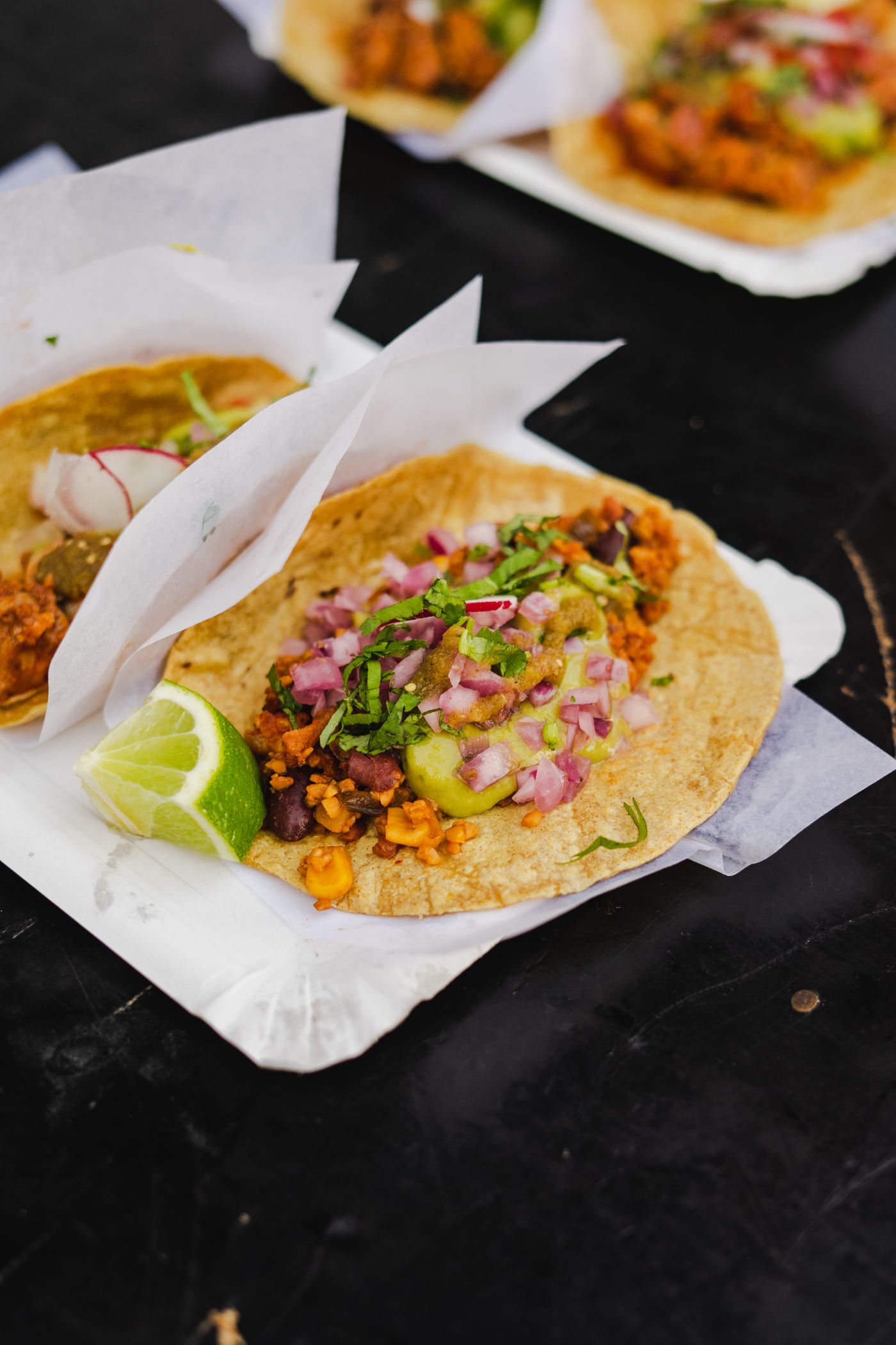 Street tacos topped with salsa, onion, and cilantro, served with lime