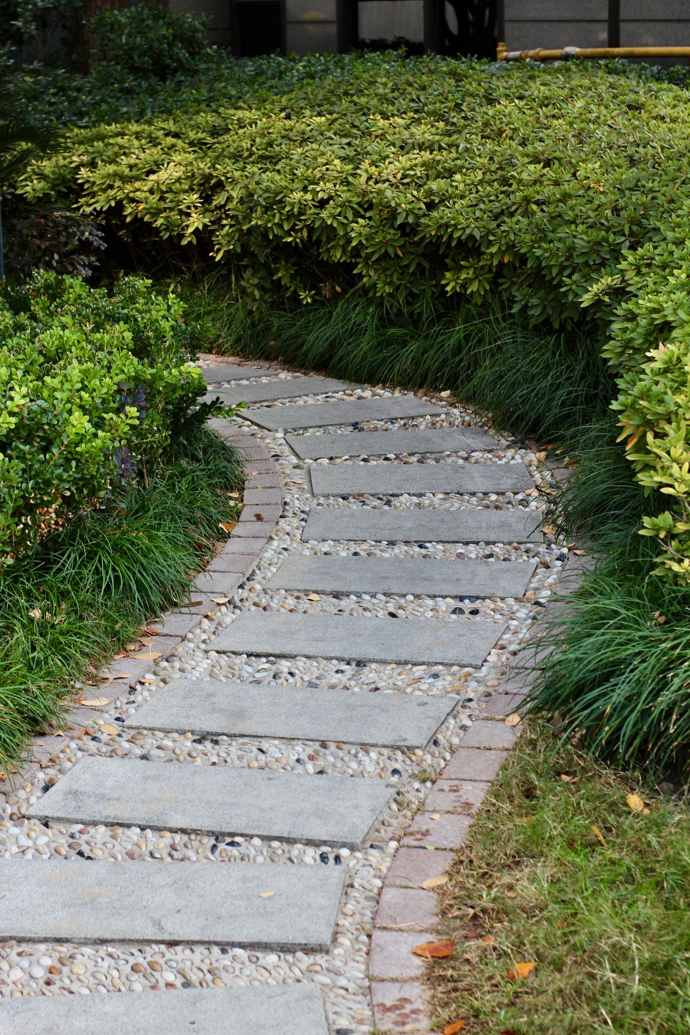 Curved stone paver walkway bordered by fresh plantings