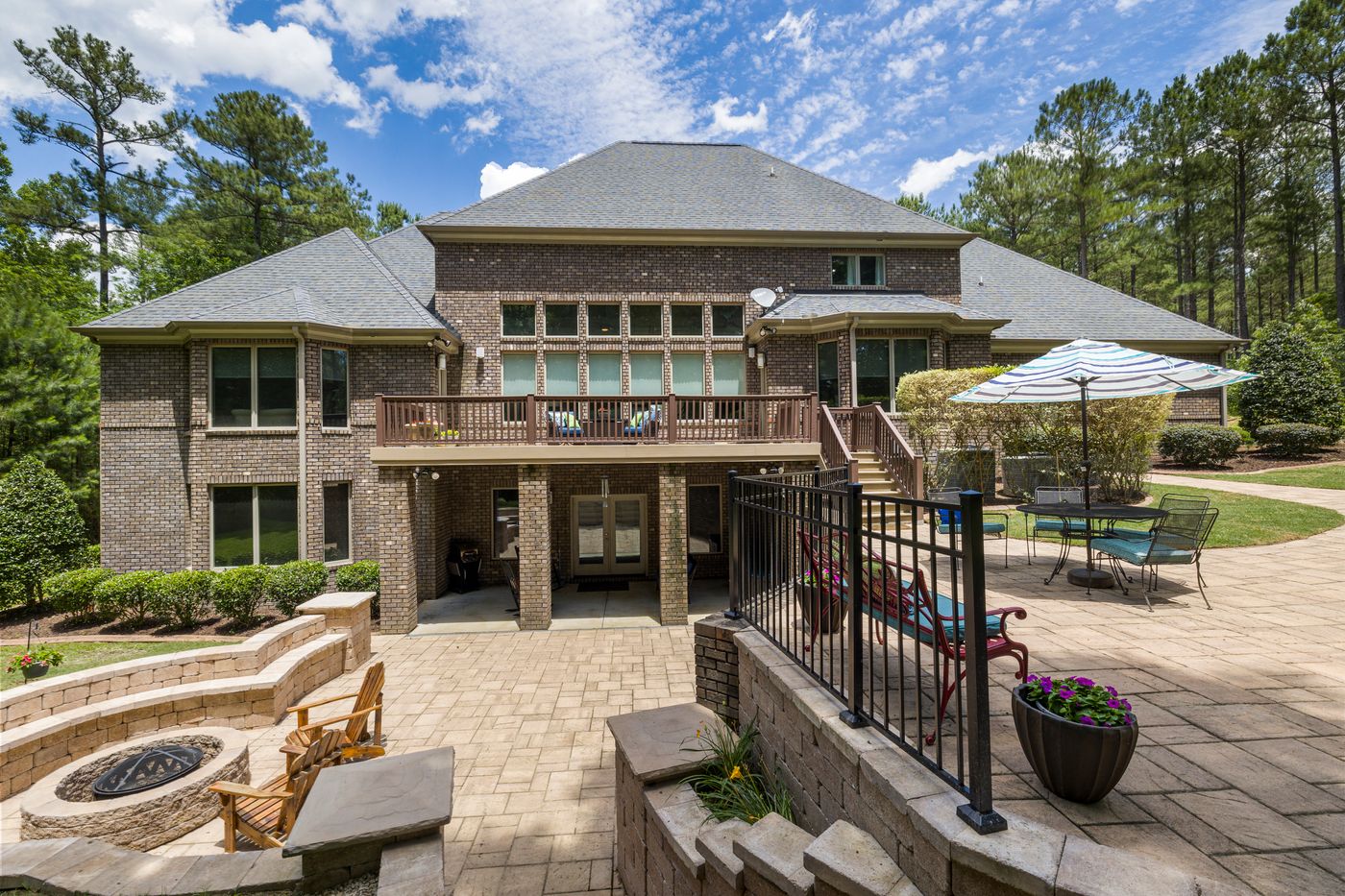 Brick home with a paver patio, stone fire pit, and landscaped beds